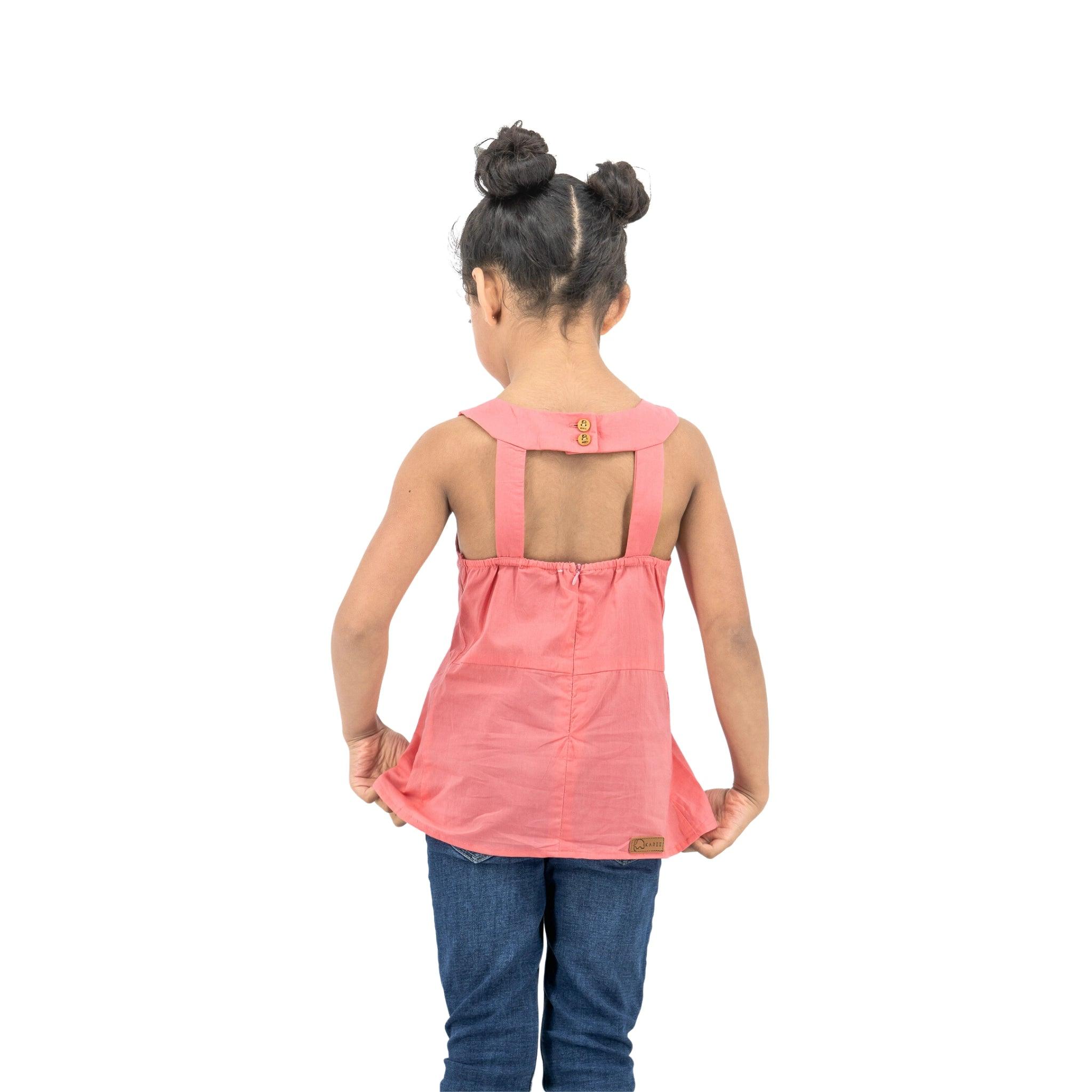 Young girl with back to camera, wearing a Karee Tea Rose Cotton Bib Neck Top for kids and blue jeans, against a white background.