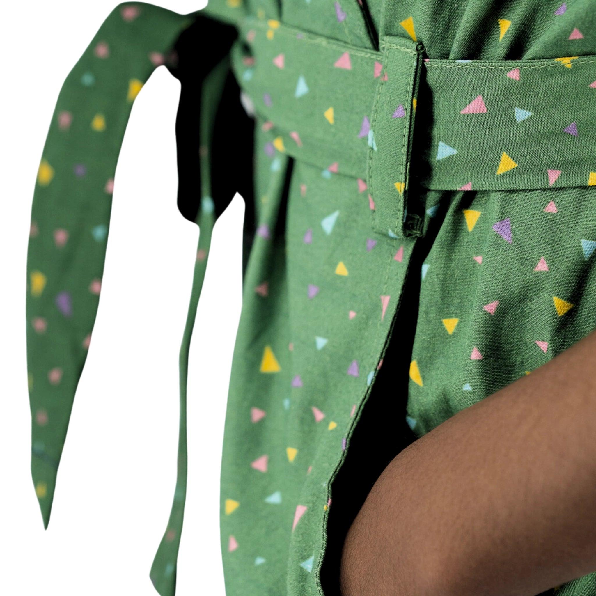 Close-up of a person wearing a Karee Green Confetti Cotton V-Neck Jumpsuit for Kids with colorful triangle patterns, partial view of their torso and arm.