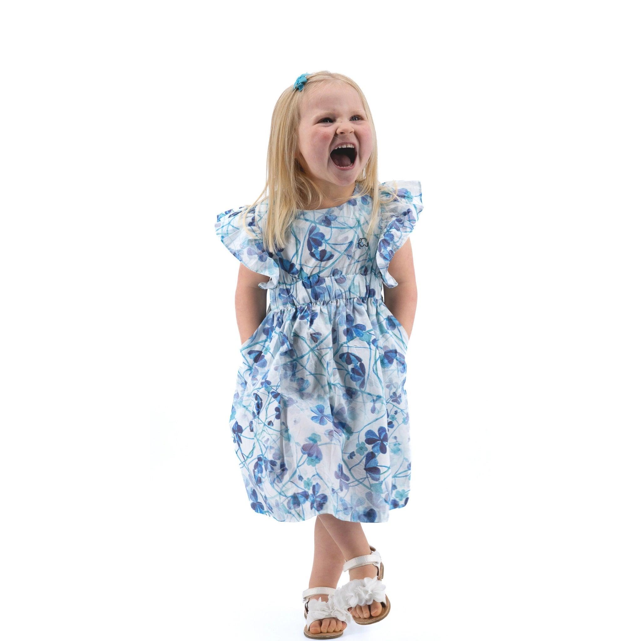 Young girl in a Karee Blue Cotton Floral Dress for Girls laughing, with a white background.