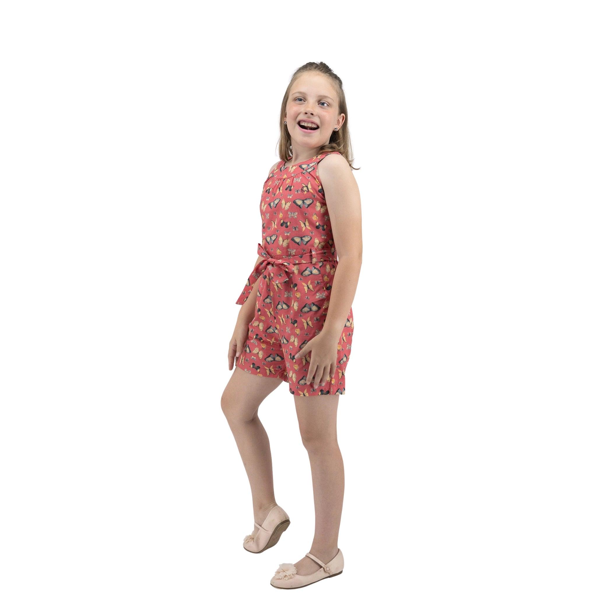 Young girl in a Karee Ruby Trek Cotton Romper smiling and posing playfully on a white background.