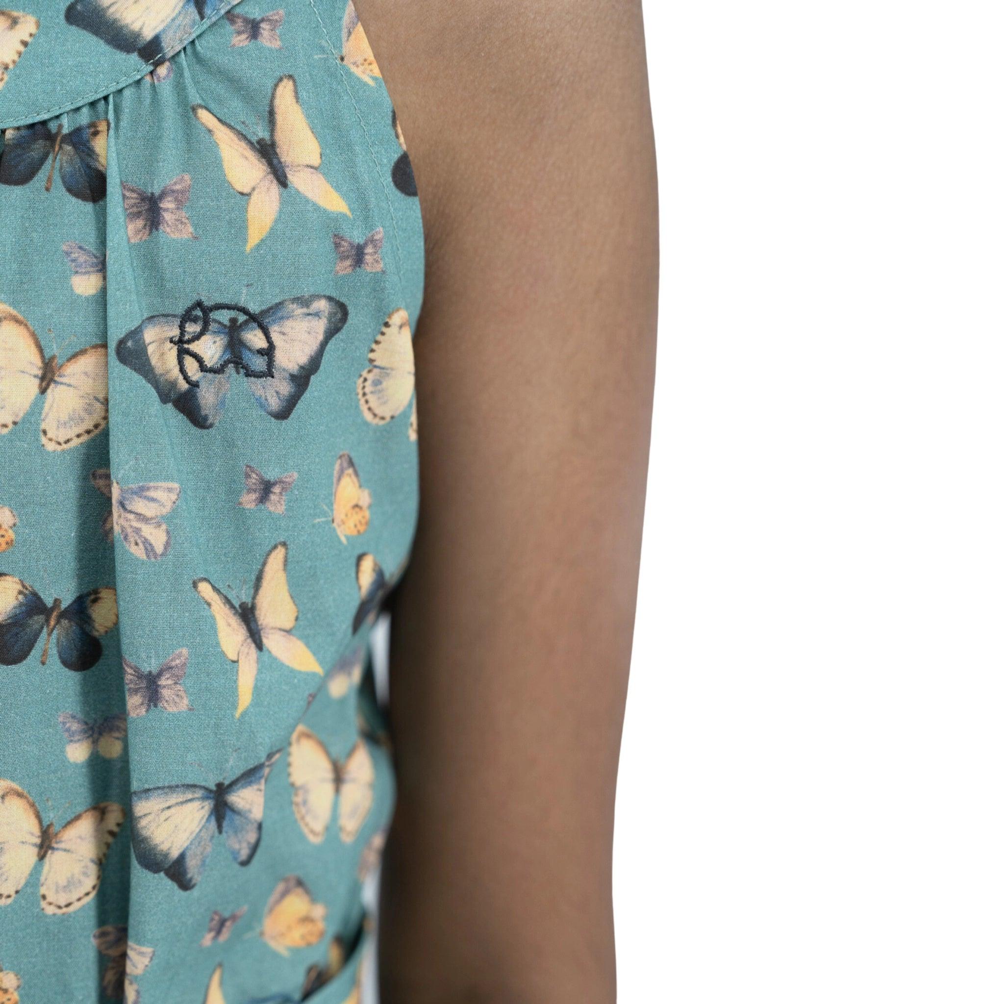 Close-up of a person wearing a Karee Blue Surf Adventure-ready Cotton Play Suit with butterfly patterned fabric, visible arm, and a small bow detail on the outfit.