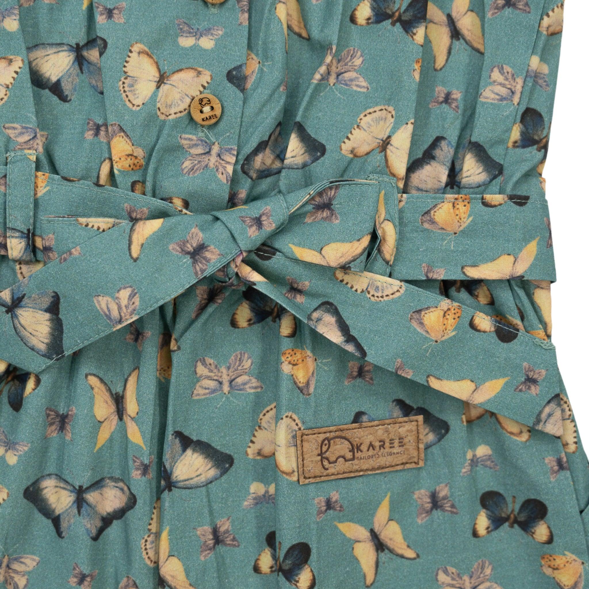 Close-up view of a Karee Blue Surf Adventure-ready Cotton Play Suit with a butterfly print, featuring a bow and a brand label stitched on.
