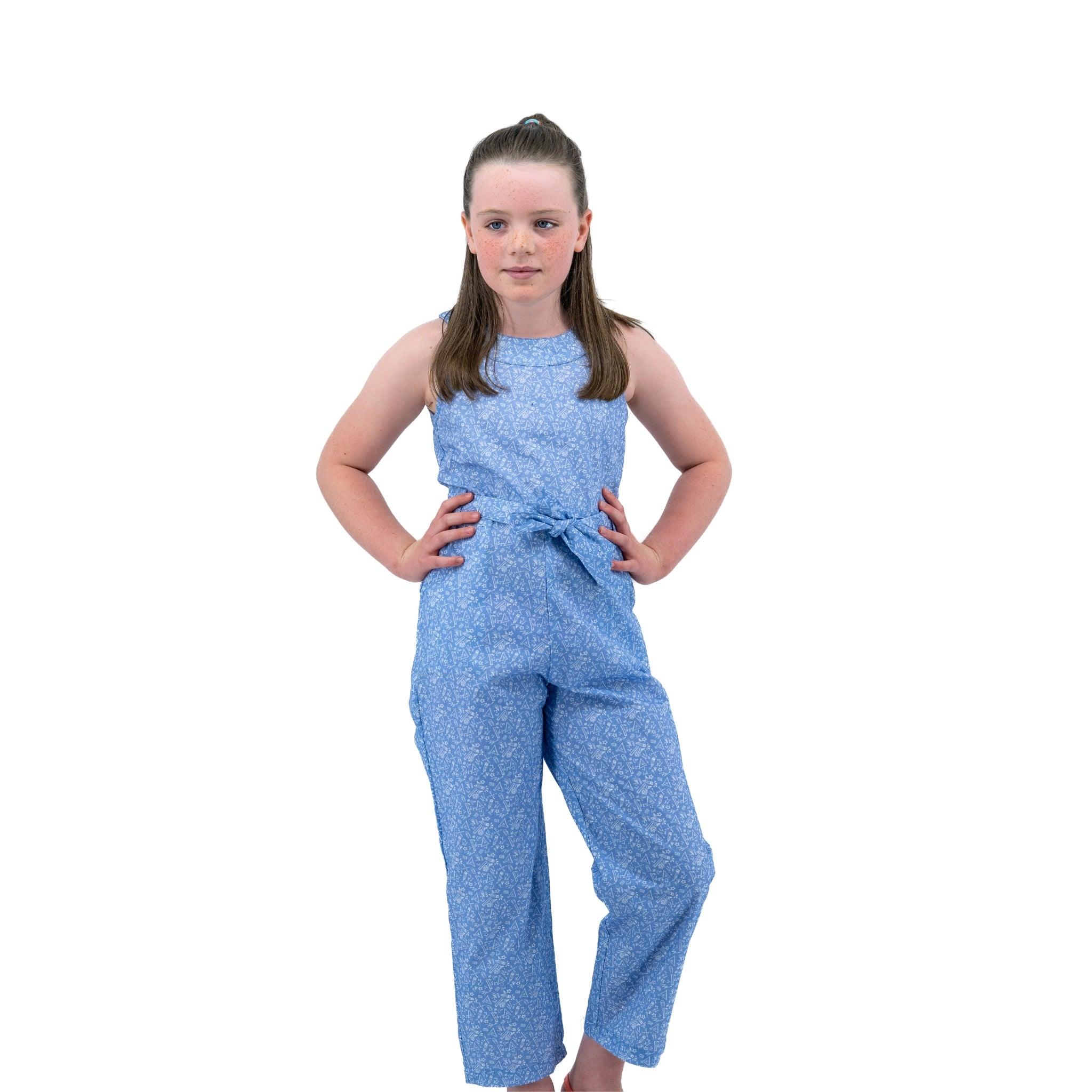 A young girl in a Karee Purple Impression Cotton Jumpsuit for kids poses with hands on hips, isolated on a white background.