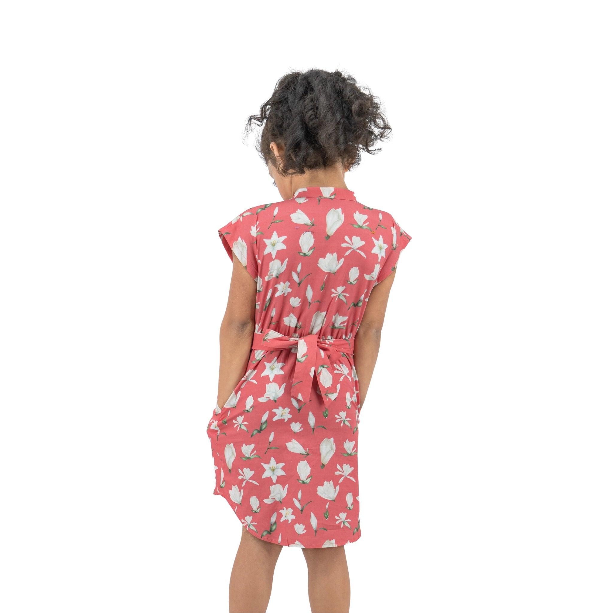 Young girl seen from behind wearing a Karee Mineral Red Lilly Blossom Cotton Shirt Dress, standing against a white background.