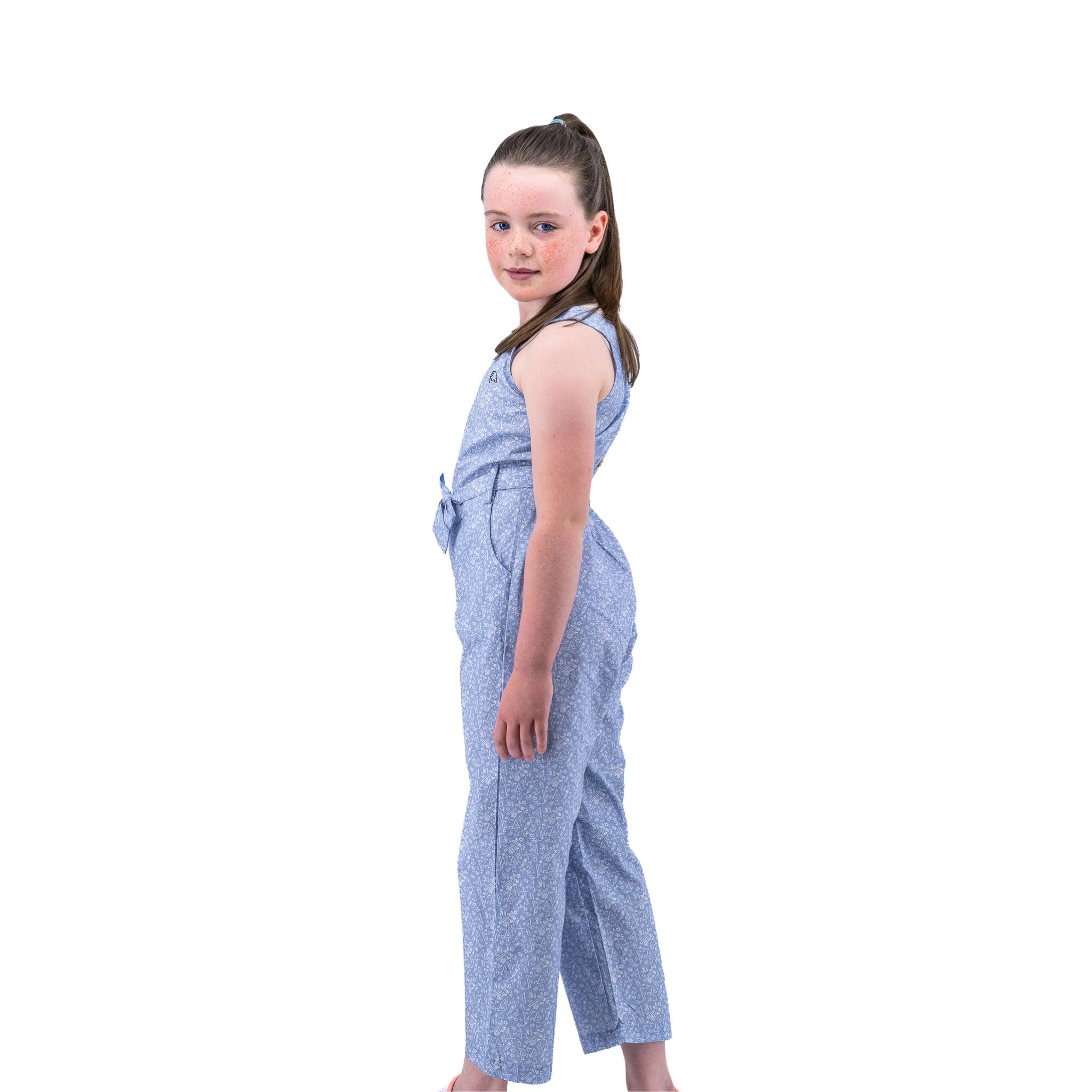 Young girl in a Purple Impression Cotton Jumpsuit for kids by Karee posing with her head turned towards the camera, standing against a white background.