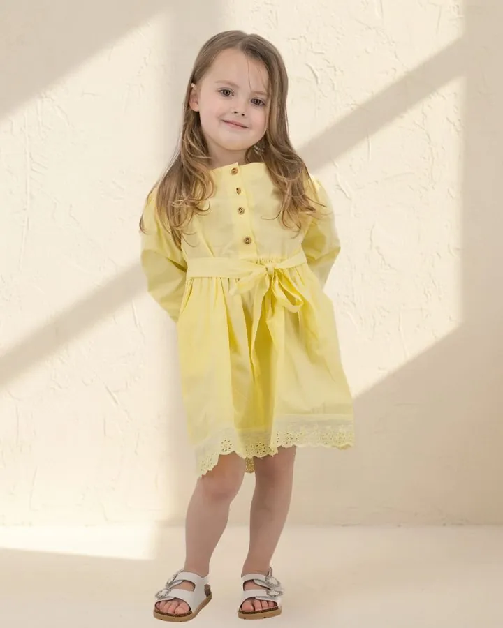 Girls' autumn dress: a girl in the Buttercup yellow long puff-sleeve cotton dress with tie belt